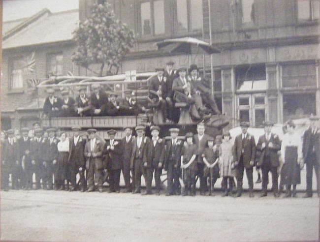 Charabanc outing probably celebrating the end of the first world war (because of the flags and the band).
